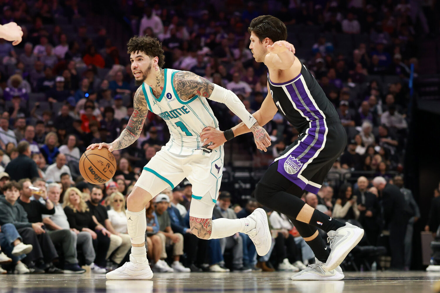 SACRAMENTO, CALIFORNIA - MARCH 11: LaMelo Ball #1 of the Charlotte Hornets is guarded by Doug McDer...
