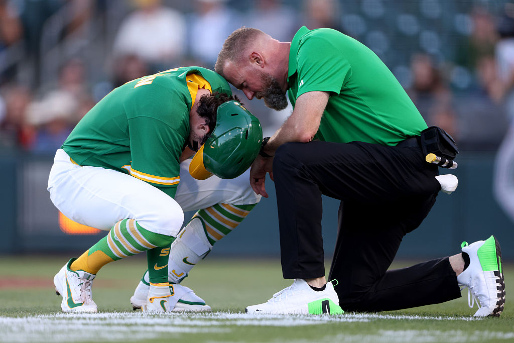 SACRAMENTO, CALIFORNIA - AUGUST 14: Jacob Wilson #5 of the Athletics is checked on by a trainer after being hit by a pitch during the bottom of the first inning against the Texas Rangers at Sutter Health Park on August 14, 2026 in Sacramento, California. (Photo by Scott Marshall/Getty Images)